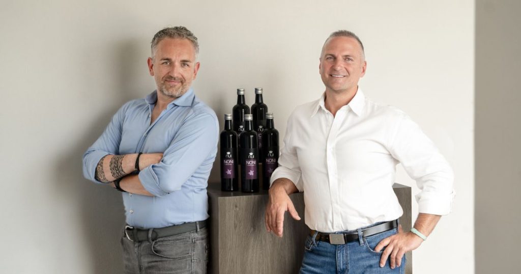 Enrico und Martin im Hemd stehen neben NUI NONI Flaschen